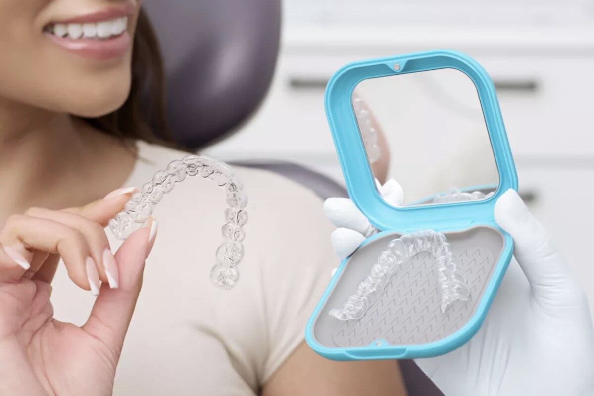 A clear Essix retainer held in the hand, with a second retainer in its storage case